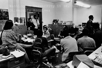 A 1968 strategy meeting of the Students of a Democratic Society. At least eight students are gathered in a room with three additional figures standing in the doorway. 