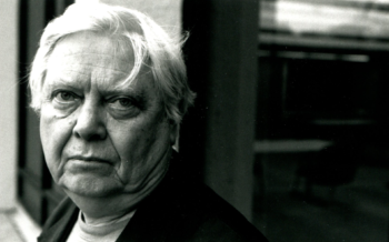 An image of William Gass, older and with white hair, looking into the camera. 
