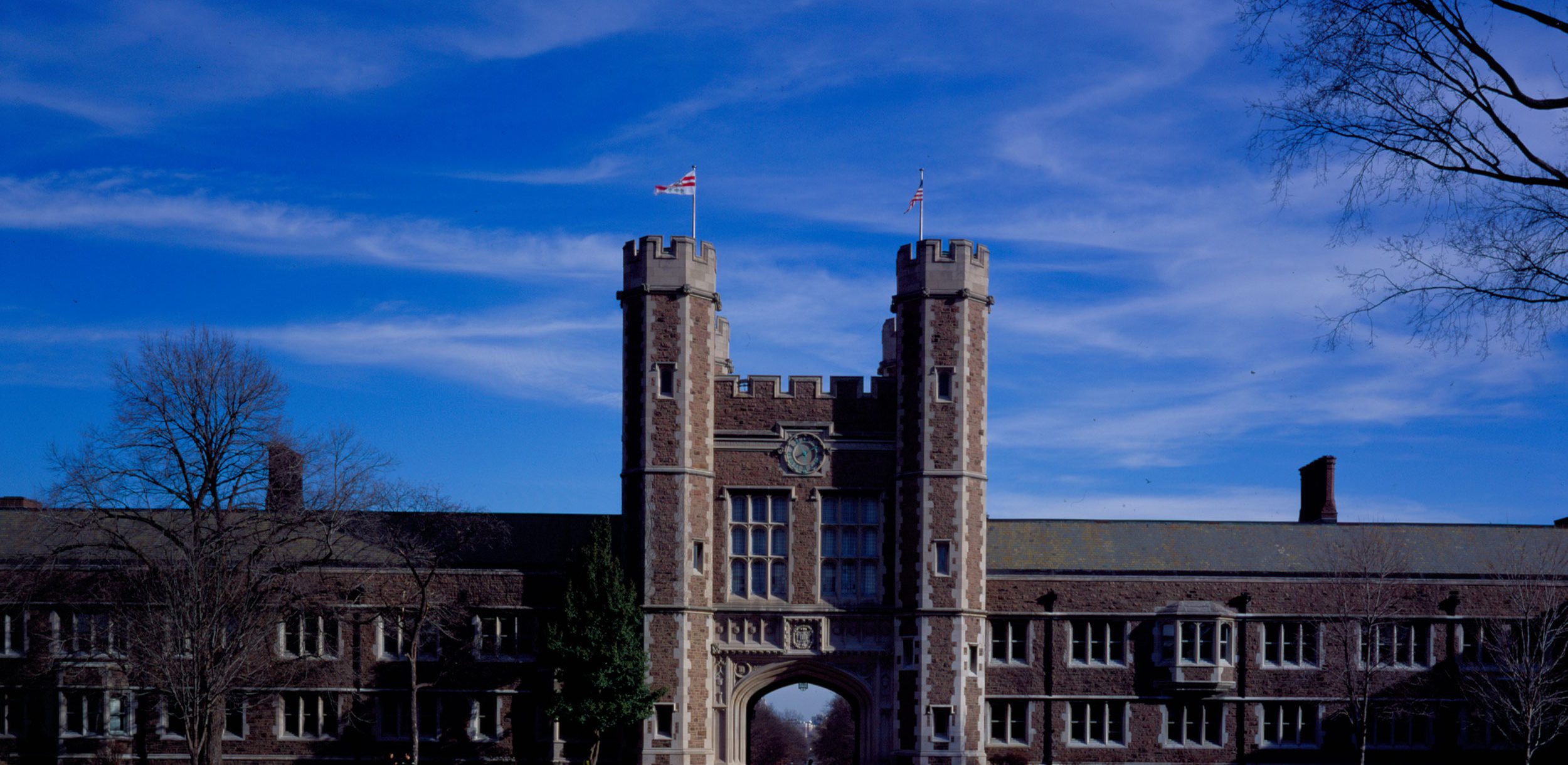 A campus photo of Brookings Hall. The walk-paths are clear and there is a rare, lovely blue sky in the background.