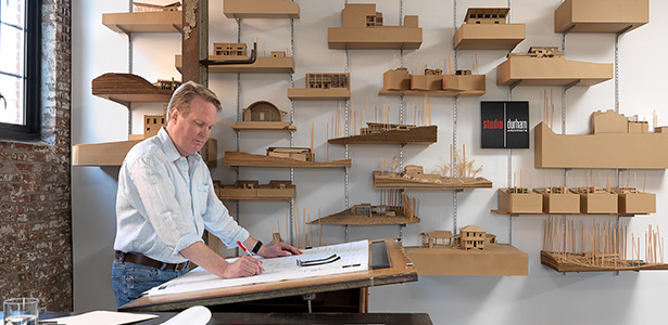 Architect and alumnus Phil Durham at a standing desk working on a design sketch in his studio.