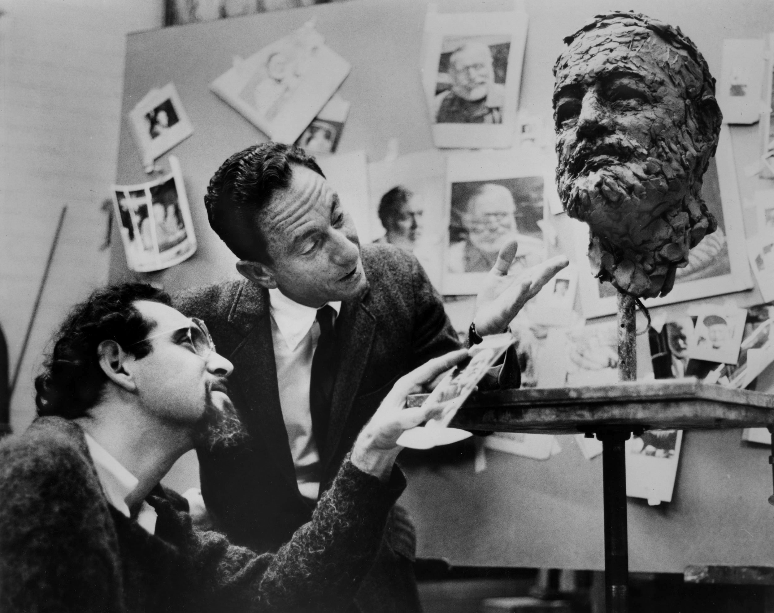 Two men inspecting a sculptor's work.