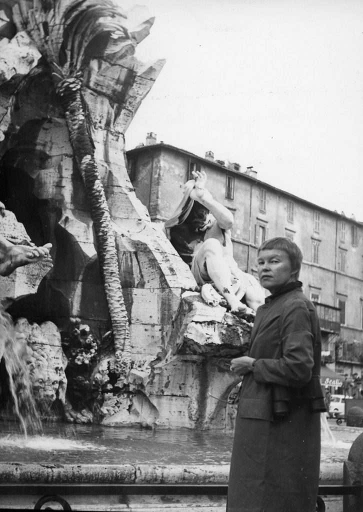 May Swenson stands alone in front of the Piazza Navona Fountain. 