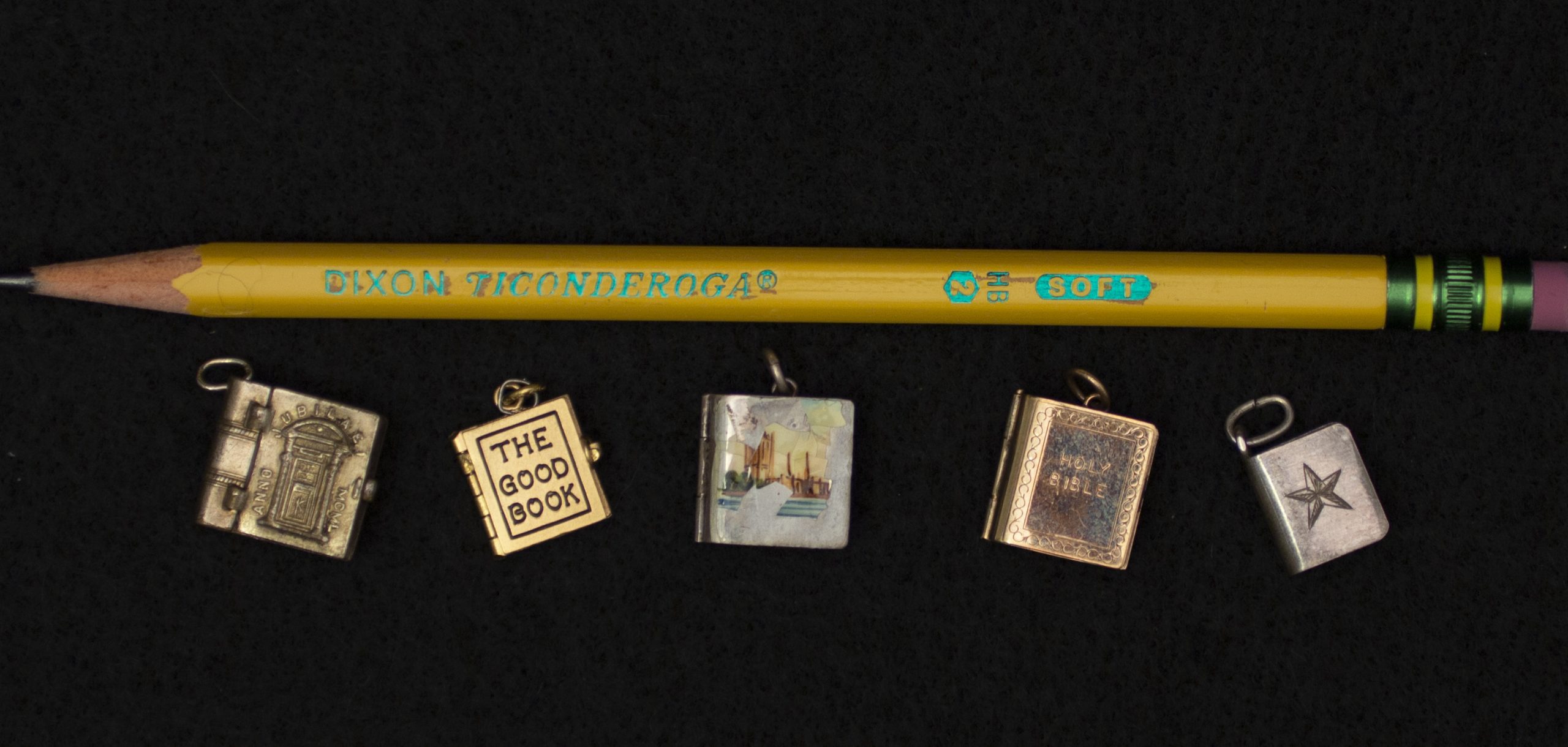 Five of the miniature books shown alongside a used #2 pencil. All five books fit along the length of the pencil with room to spare.