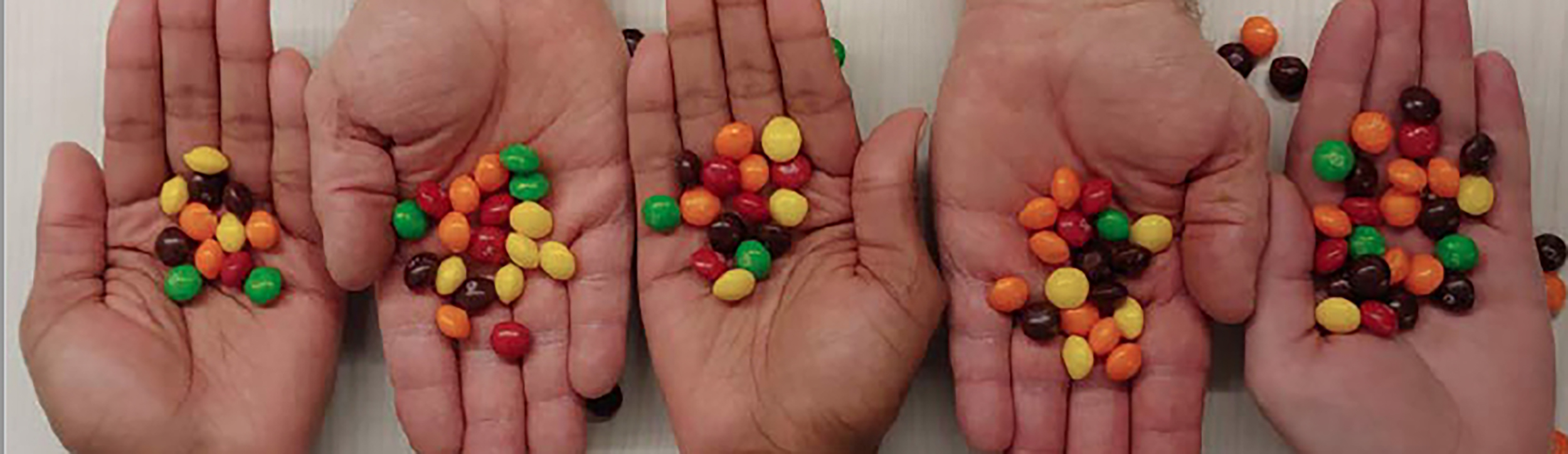 Five hands with non-organized (multicolored) skittles in each representing unorganized data.