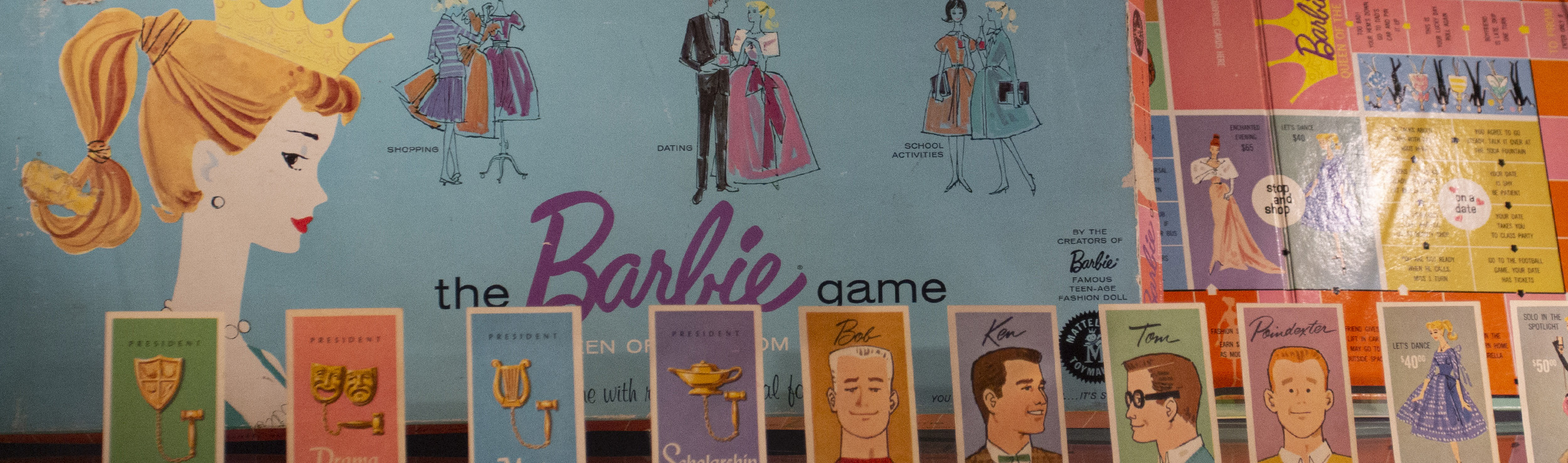 A corner photo of The Barbie Game board, which depicts Barbie in a crown along with numerous landing-squares featuring both items and suitors for Barbie.
