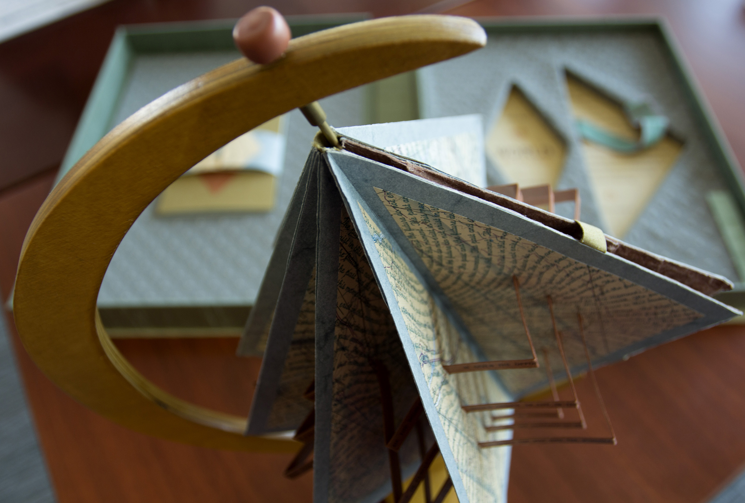 A book in the form of an origami folding displayed on a globe stand.