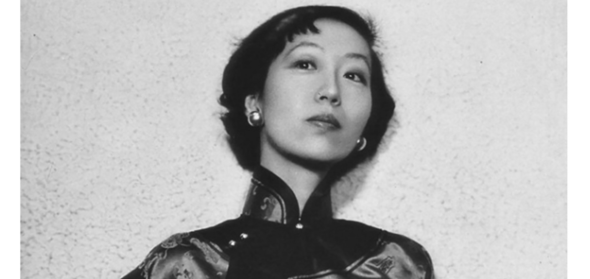 Eileen Chang has short, cropped hair and is wearing oversized earrings with a high neck, three-quarter length sleeved silk top.