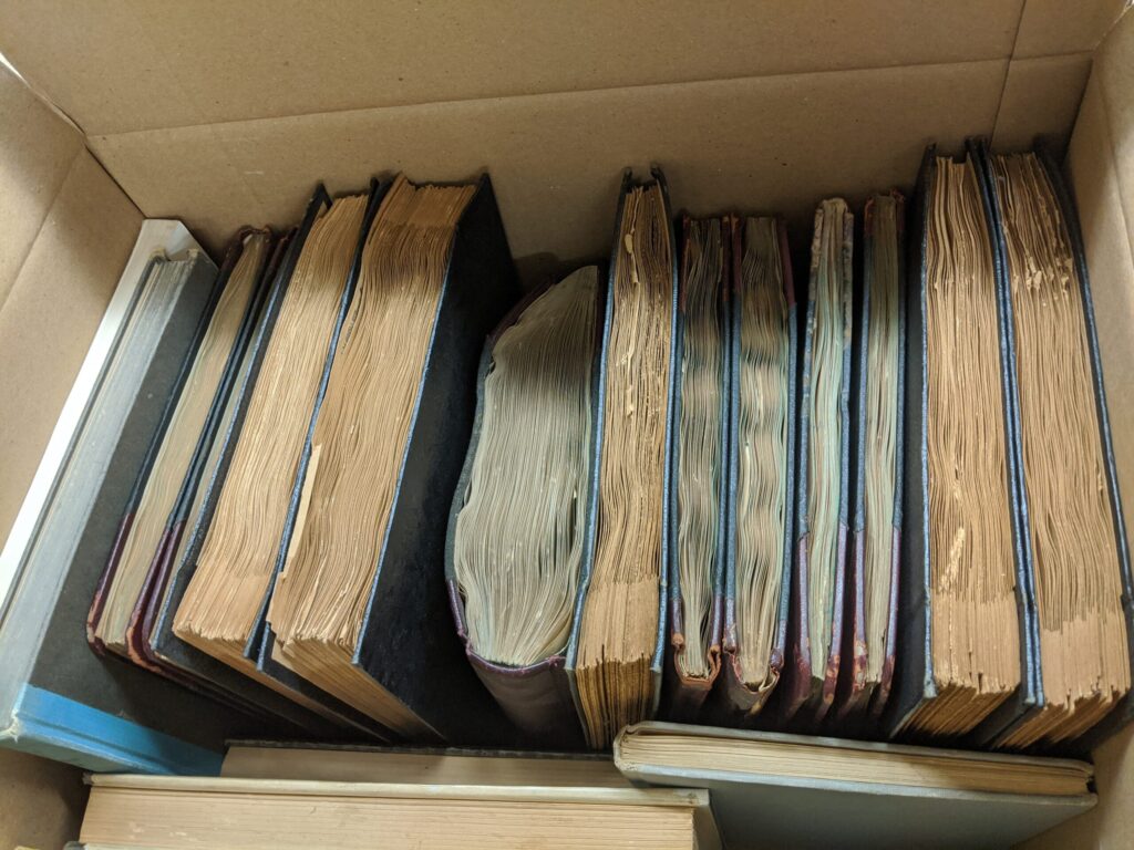 Sixteen filled scrapbooks of various sizes packed within a collection box.