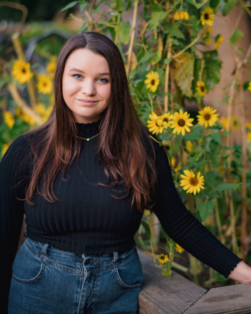 Mendel Sato Research Award 2021 winner Olivia Danner, Class of 2024. Danner is posed in front of sunflowers for this photo.