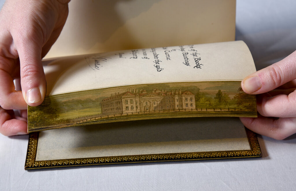 The fore edge painting shows a grand country estate.