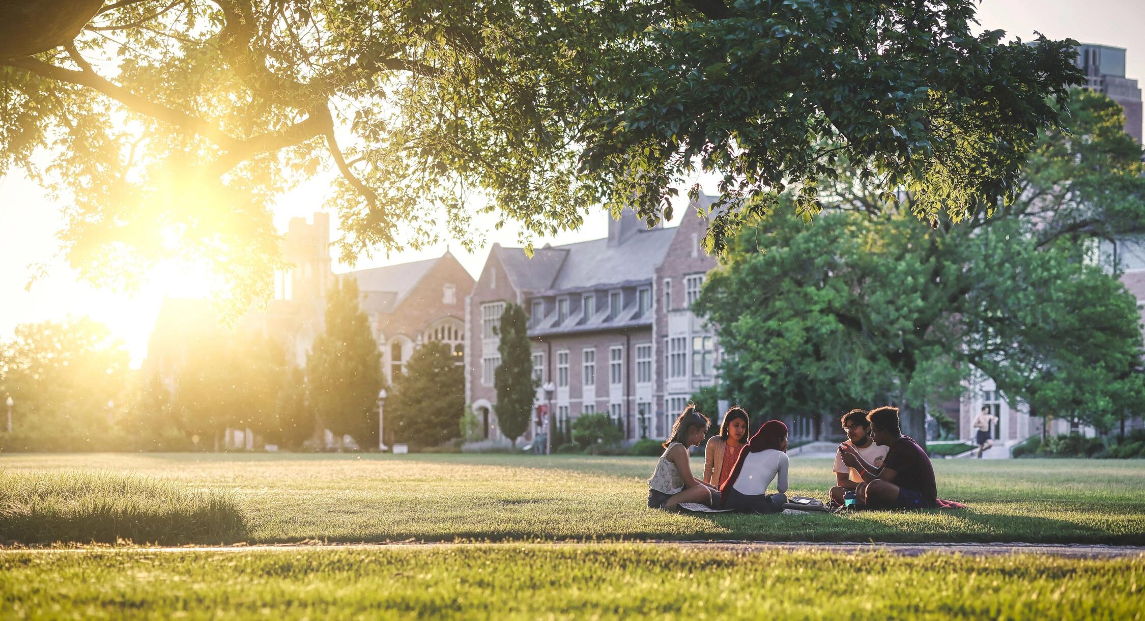 Students sitting on a campus quad during a sunny day.