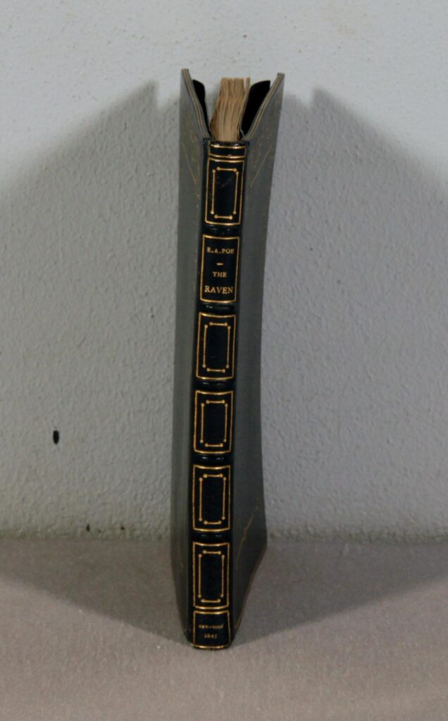 The image shows The Raven before conservation efforts were made. The book is severely warped due to water and bends alarmingly to the right due to the damage.