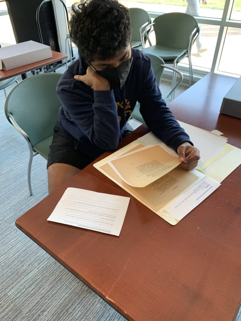 A student in the Special Collections classroom examines original drafts and typescripts of poems by May Swenson and James Merrill