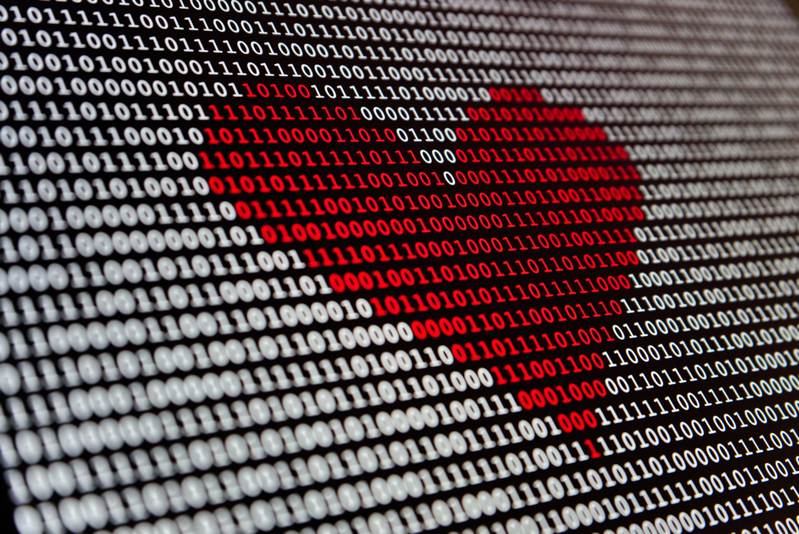 A heart drawn in red over a background of binary code.