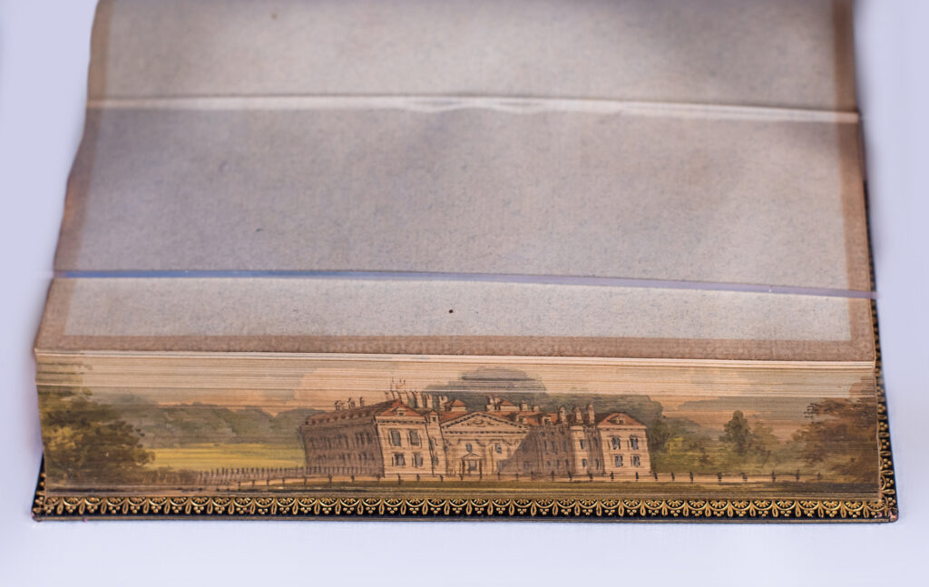 Fore-edge painting on Highways and Byways depicting a multi-story manor house in the countryside.