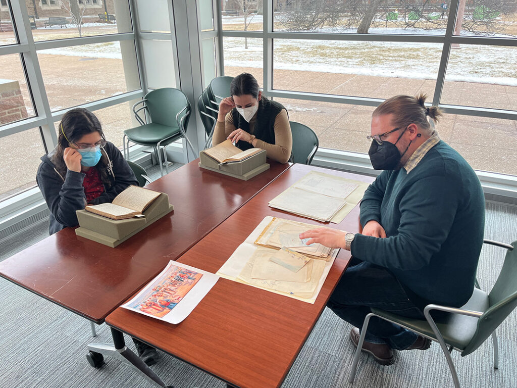 Students and a professor studying James Merrill's papers in Olin Library.
