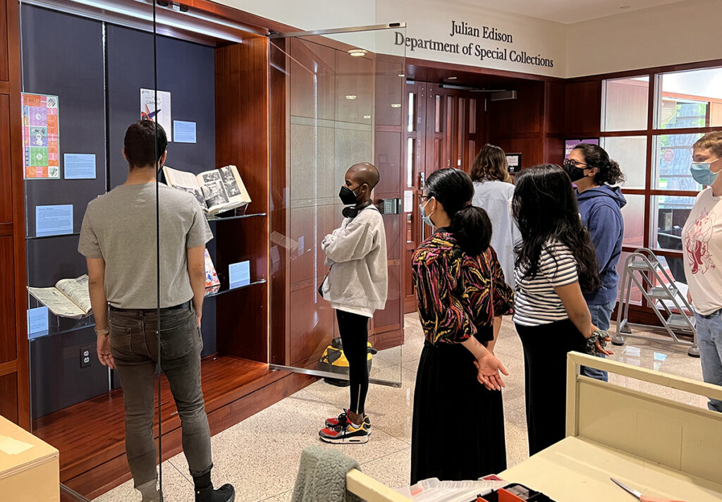 Students gather around an open, floor-to-ceiling exhibitions display case outside of the Olin Library Julian Edison Department of Special Collections.