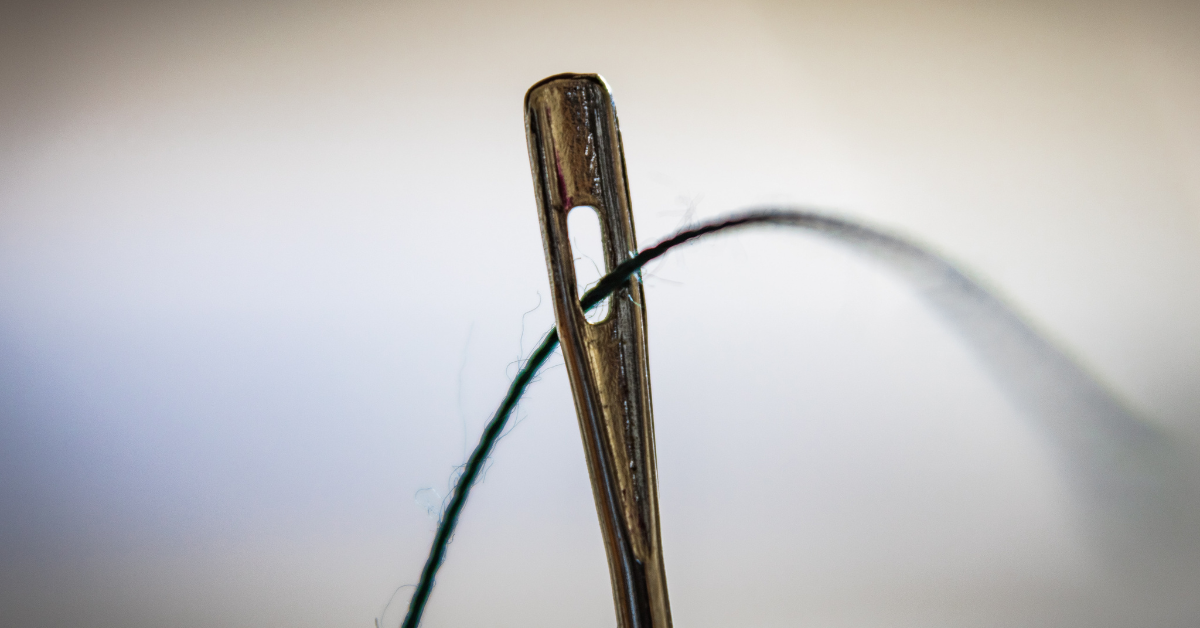 A close up of thread through a needle.
