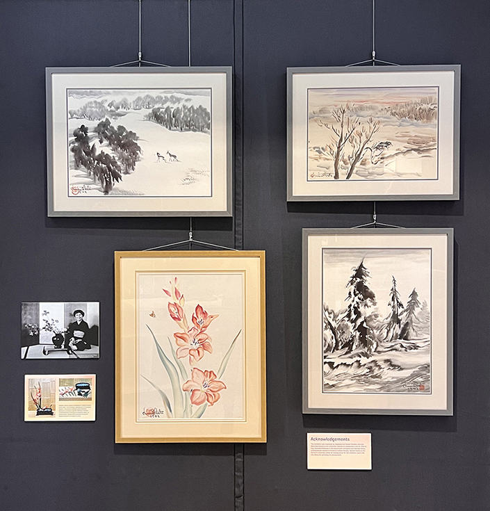 The second half of the display case for the Chiura Obata, an Artist Behind Barbed Wire exhibition. Four paintings are shown here alongside a black and white photo and two informational plaques.