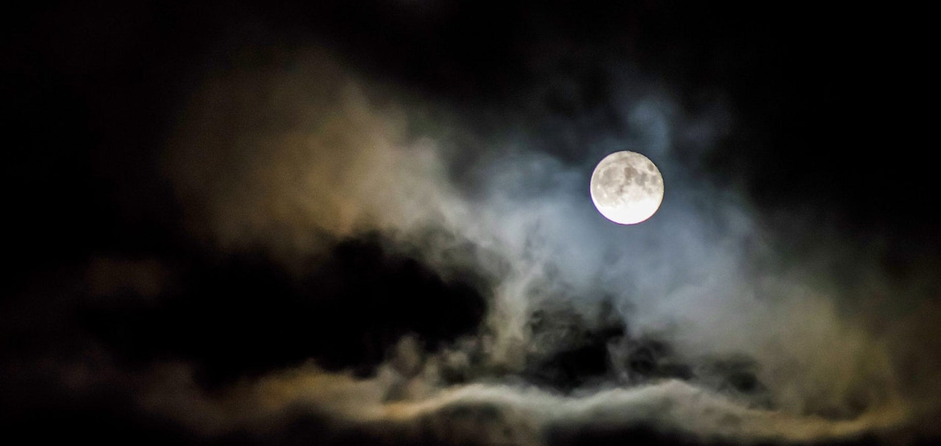 A photograph of a full moon on a cloudy night.
