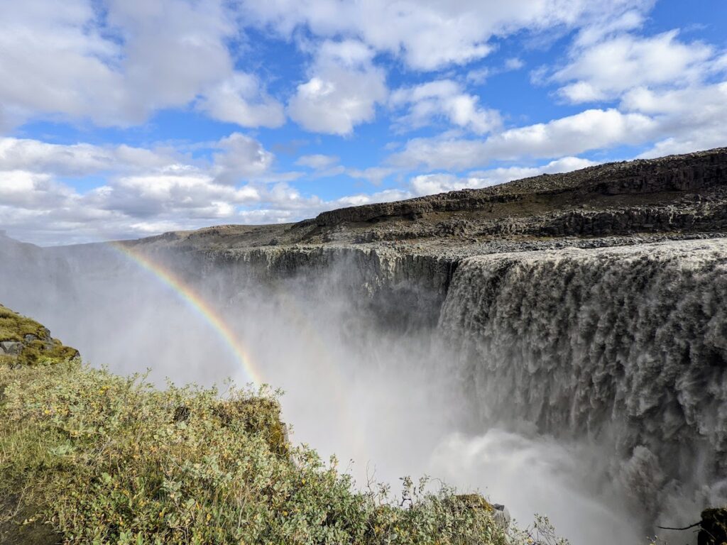 Waterfall under blue skies with a rainbow.