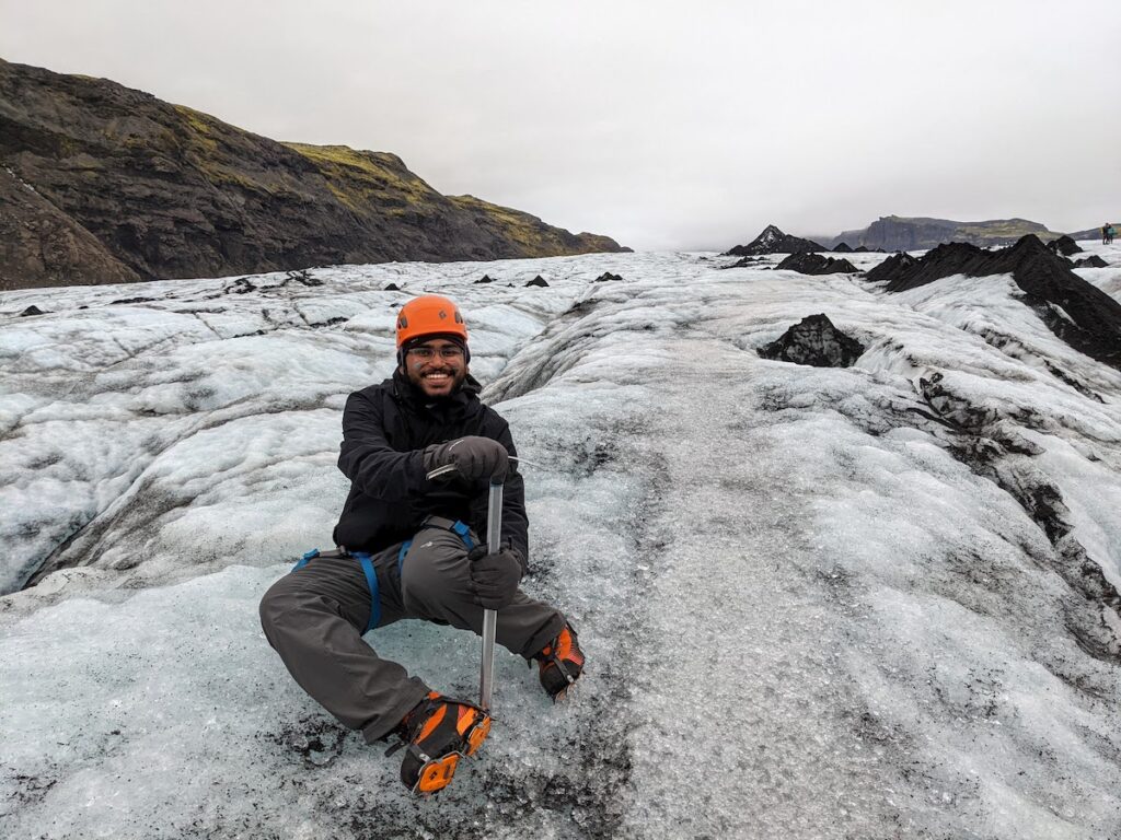 A man sitting on the slope of an icy glacier