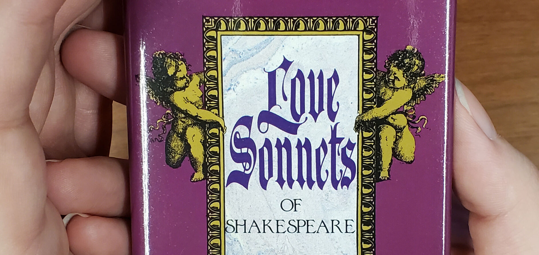 A miniature book titled Love Sonnets of Shakespeare held in the palm of someone's hand.