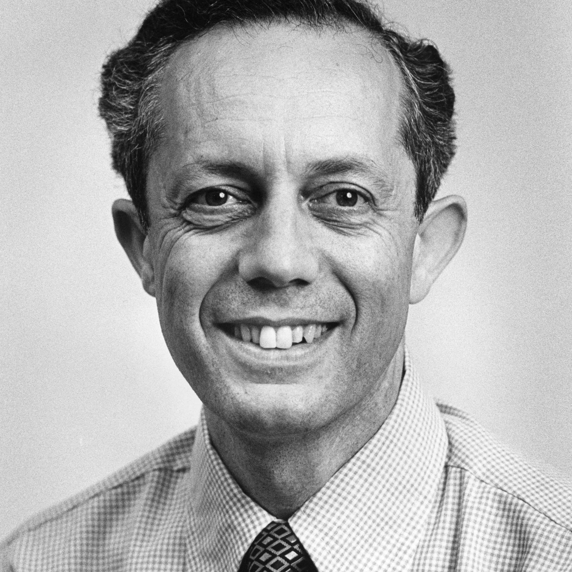 A black and white portrait of professor of physics Michael W. Friedlander wearing a button-up shirt and tie.