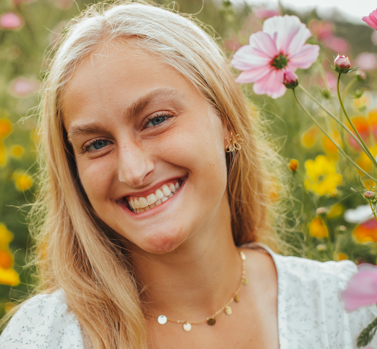 Portrait shot of a smiling woman in a field of flowers.