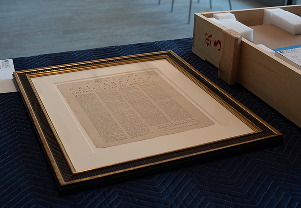A framed Rogers Broadside just removed from its travel crate on a table within Special Collections.