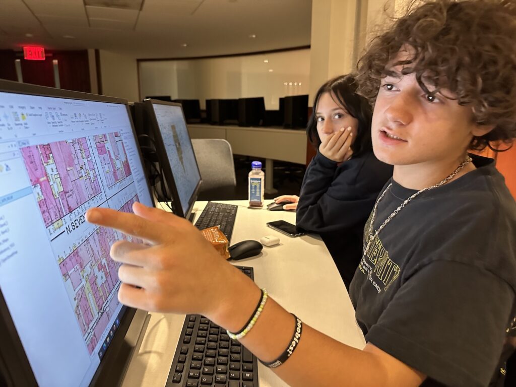 Two students looking at maps on computers.