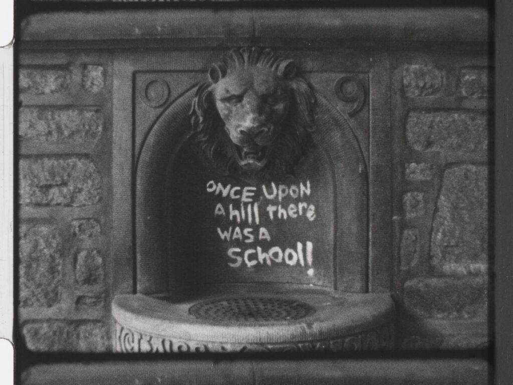 A lion gargoyle on a stone wall with the inscription," Once Upon a hill there was a School."