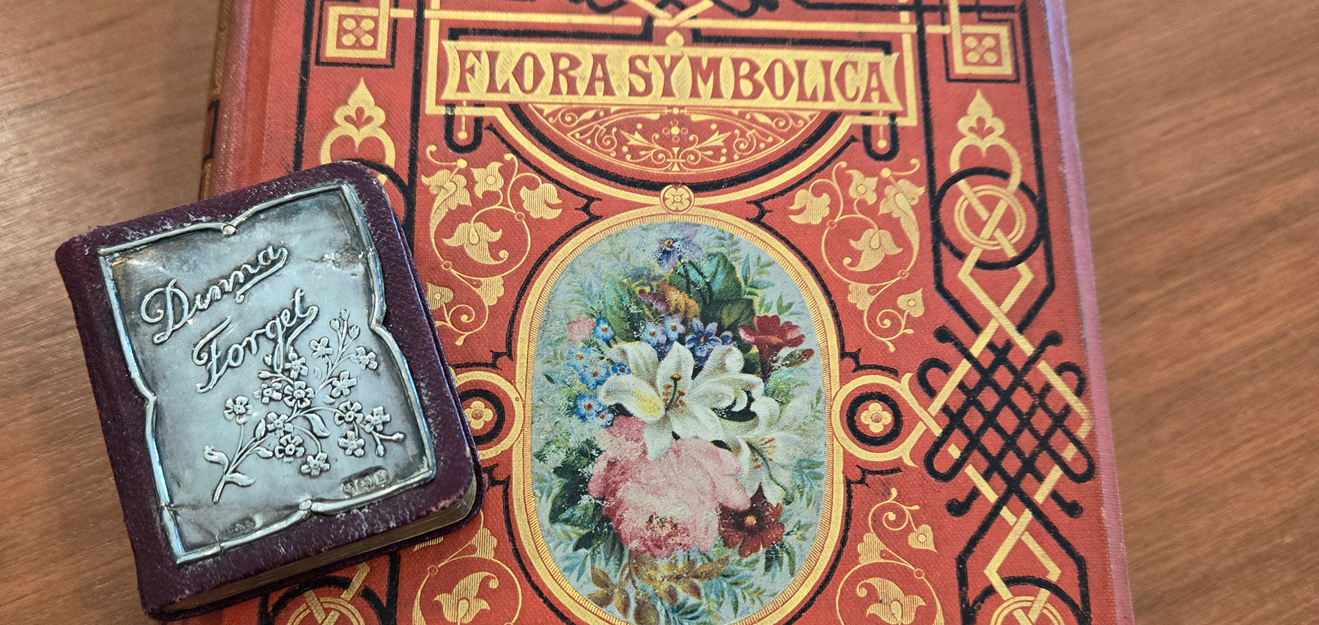 Beautifully decorative cover of Flora Symbolica with a miniature book alongside it.