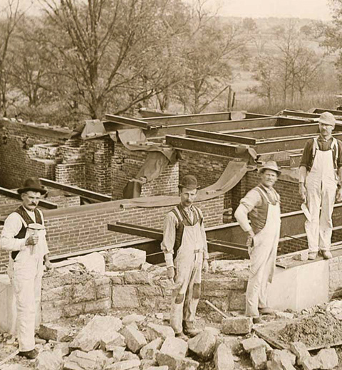 A closeup of four construction workers on-site at the foundations of a building on the Danforth Campus circa 1900.