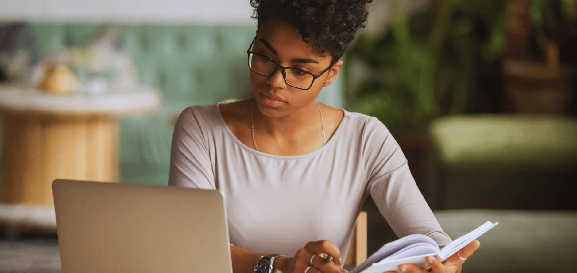 Stock photo of student writing in notebook and looking at laptop computer