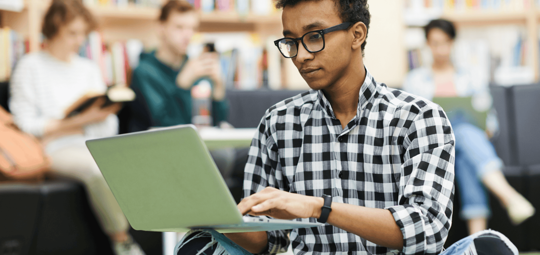 Stock photo of student typing on laptop in library