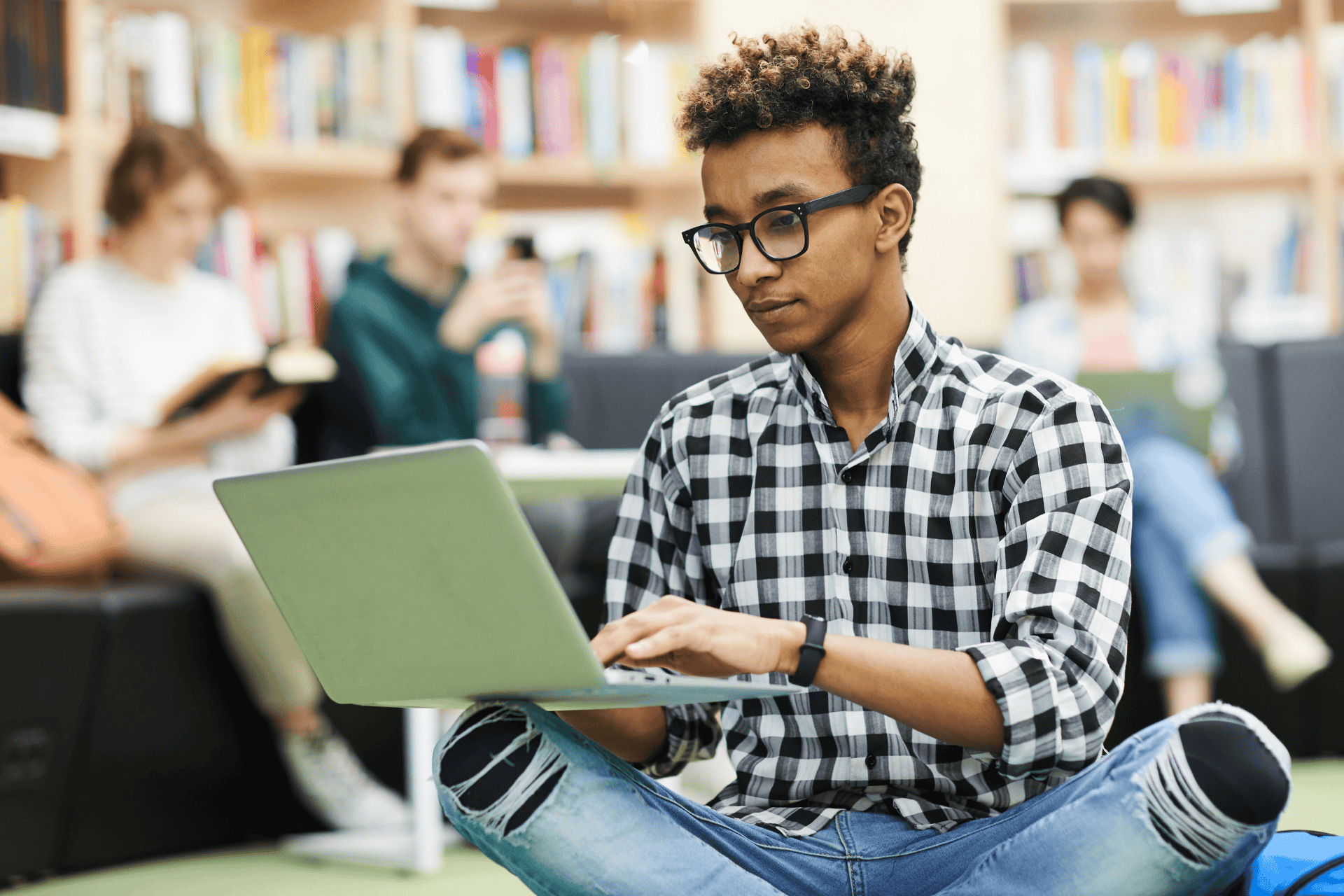 Stock photo of student typing on laptop in library