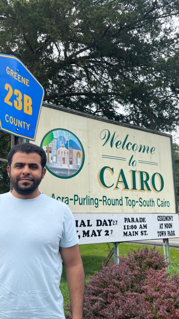 Author in front of a "Welcome to Cairo" sign