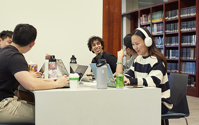 Five students studying and chatting at a table in Olin Library.